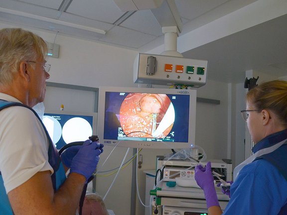 Ein Arzt und eine weitere medizinische Fachkraft sthen im Untersuchungsraum vor dem Monitor