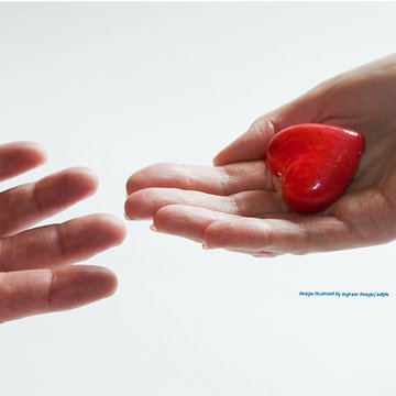 Zwei aufgehaltene Hände, auf der einen Hand liegt ein kleines rotes Herz.