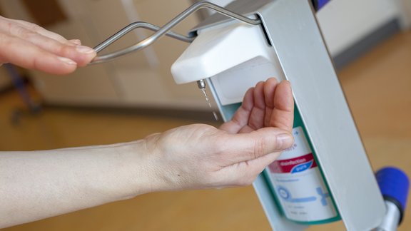 Hände betätigen einen Desinfektionsspender