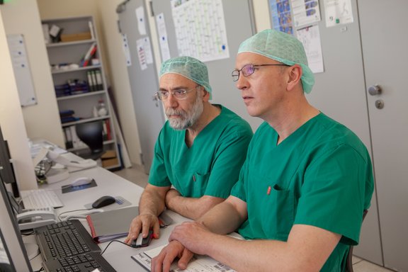 Zwei Operateure der Gefäßmedizin sehen sich Untersuchungsergebnisse am Monitor an