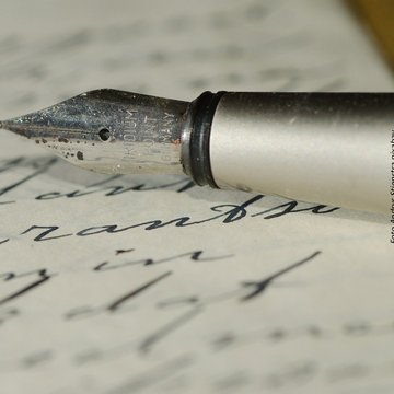 Handschriftlich beschriebenes Blatt Papier und die Spitze eines Füllfederhalters
