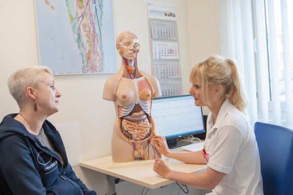 Beratungsgespräch anhand eines Körpermodels zwischen Ärztin und Patientin im  Behandlungszimmer