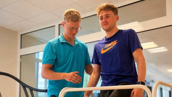 Leiter des MediFit, Jannik Billigmann, zeigt einem Patienten Übungen am Posturomed (Wackelbrett)