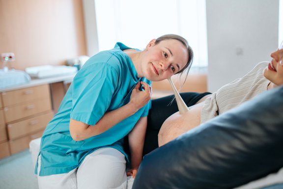 Hebamme hört den Bauch der werdenden Mutter ab.