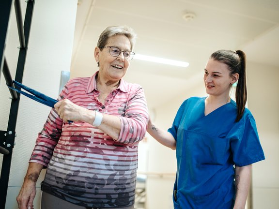 Pflegekraft hilft älterer Dame mit Schulter