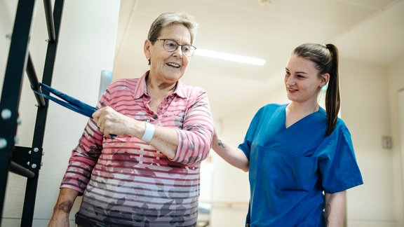 Pflegekraft hilft älterer Dame mit Schulter