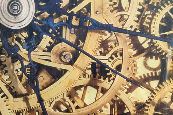 Zahnräder einer Uhr greifen ineinander, darüber sind blaue Zeiger abgebildet.