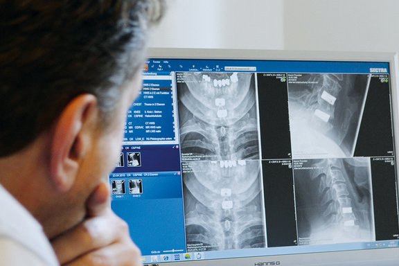 Mediziner schaut sich am Bildschirm Röntgenbilder an.