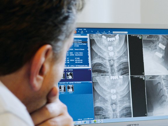Mediziner schaut sich am Bildschirm Röntgenbilder an.