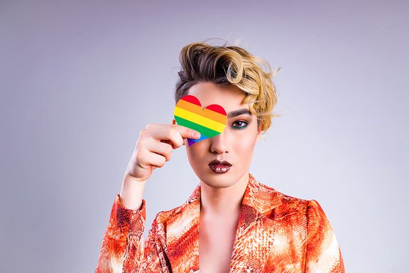 Person hält Transgenderherz vor dem Auge