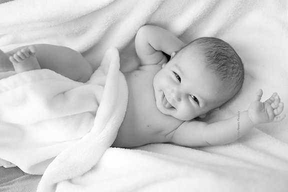 Schwarz-Weiß-Foto eines fröhlich lächelnden Babys.
